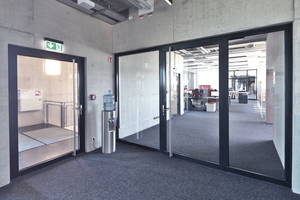  Zugang zum Bürobereich mit transparenten Stahlrohrrahmentüren (einflügelige Tür mit ei-nem Seitenteil links und rechts). 