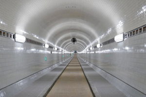  Die Oströhre des sanierten St. Pauli-Elbtunnels mit Entrauchungsventilator an der Tunneldecke. Um Rauch sicher abführen zu können, „hört“ der Ventilator auf eine Entrauchungssteuerung mit neuester Technologie. 