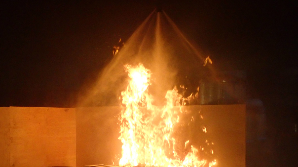 Loderndes Feuer wird mit Wassernebel von oben besprüht